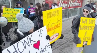  ?? FRANK GUNN, CANADIAN PRESS ?? Protesters stand outside a Tim Hortons in Toronto as part of National Day of Action in Support of Tim Hortons workers on Friday. About 50 demonstrat­ions took place across Canada.