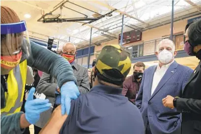  ?? MICHAEL ROBINSON CHAVEZ/THE WASHINGTON POST ?? Gov. Larry Hogan, center right, Prince George’s County Executive Angela Alsobrooks, right, and Pastor John K. Jenkins, Sr., center left, watch Tuesday as a man receives a COVID vaccine at the First Baptist Church of Glenarden.