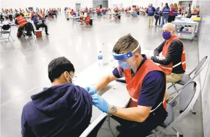  ?? STEPHEN M. KATZ/STAFF FILE ?? A COVID-19 vaccinatio­n clinic underway at the Virginia Beach Convention Center in January. Virginia has 8.5 million residents and most have said they want the shot. It’s rare there’s an extra dose, but when it happens, vaccine clinic workers scramble to find someone for it.