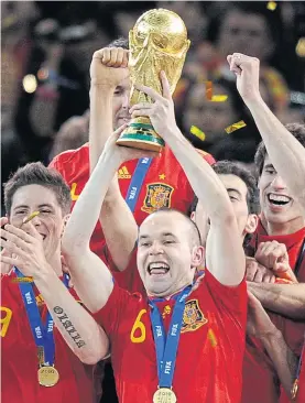  ??  ?? Iniesta holds up the Fifa World Cup trophy in 2010.