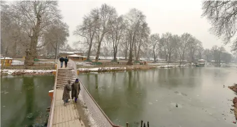  ?? AFP ?? Kashmiri men walk on a foot bridge over a frozen portion of Dal Lake in Srinagar on Saturday. —