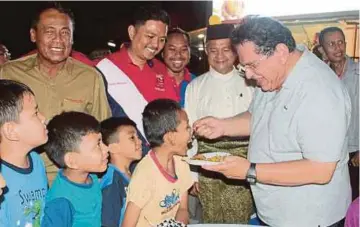  ??  ?? TENGKU Adnan menyuapkan makanan kepada seorang kanak-kanak dalam majlis meraikan sambutan hari lahir bersama penduduk Putrajaya.