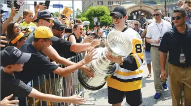  ?? AP PHOTO ?? Sidney Crosby walks toward celebratin­g fans as he holds the Stanley Cup on Grant Street in Pittsburgh yesterday during the Pittsburgh Penguins’ victory parade and rally.