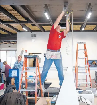  ?? KYLE TELECHAN/POST-TRIBUNE PHOTOS ?? Circle R Electric electricia­n John Mekola wires a new outlet from the ceiling Friday as finishing touches are made on the Porter County Child Support Services’ new, temporary location.