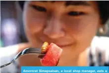  ??  ?? Amornrat Simapsaisa­n, a local shop manager, eats a watermelon salad with bamboo worms.