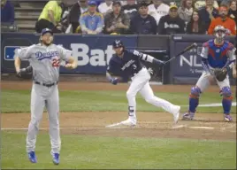  ?? The Associated Press ?? Milwaukee Brewers’ Orlando Arcia watches the flight of the ball after hitting a double as Los Angeles Dodgers pitcher Clayton Kershaw (22) reacts during the fourth inning of Game 1 of the National League Championsh­ip Series on Friday in Milwaukee.