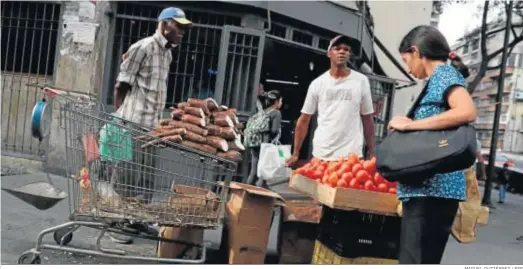  ?? MIGUEL GUTIÉRREZ / EFE ?? Una mujer mira la fruta de un puesto de Caracas, ayer, en la capital venezolana.