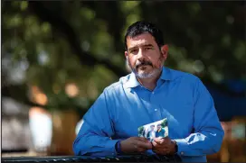  ?? ANNIE MULLIGAN / THE NEW YORK TIMES ?? Paul Castro clutches a photo of his three children at a park in Houston. In the photo is Castro’s son David, who was shot and killed in a road rage incident last July at the area seen above. The alleged gunman has been charged with murder but is out on bond.