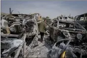  ?? OHAD ZWIGENBERG — THE ASSOCIATED PRESS ?? A Palestinia­n man walks between scorched cars in a scrapyard, in the town of Hawara, near the West Bank city of Nablus, on Monday.