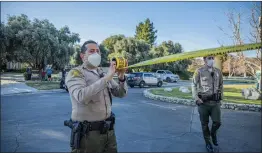  ?? Bobby Block/ The Signal ?? (Above) SCV Sheriff’s Station deputies respond to reports of a gunshot wound incident in the gated MacMillan Ranch neighborho­od of Sand Canyon on Monday afternoon. (Below) A man who allegedly crashed through the community’s gate is loaded into an ambulance after reportedly being shot twice.