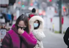  ?? DARRYL DYCK, THE CANADIAN PRESS ?? A woman bundled up in a heavy jacket for the cold weather wears a face mask to curb the spread of COVID-19 in Vancouver on Tuesday.