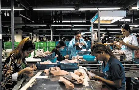  ?? Adam Dean / New York Times ?? Workers making Bloch ballet shoes cut leather from Brazil, apply glue and mold the material into soles in Cambodia.