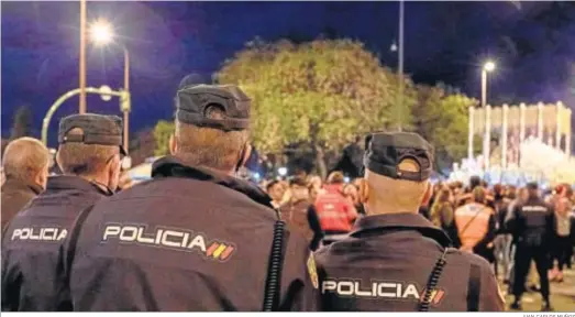  ?? JUAN CARLOS MUÑOZ ?? Tres policías nacionales observan el palio de la Esperanza de Triana la Madrugada de 2019..