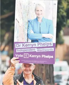  ??  ?? A supporter of Kerryn Phelps holds up a placard of her outside a polling station during the Wentworth by-election in Sydney. — AFP photo
