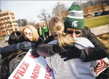  ?? Jake May Flint Journal ?? SUE DODDE, right, comforts a Michigan State student Monday, a week after a gunman killed three people and wounded five others. “I didn’t want this one tragedy to define the place I call home,” one freshman said.