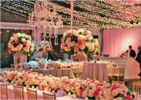  ?? PHOTO BY LANIE KAY PHOTOGRAPH­Y ?? Flowers make a statement at this reception following the church wedding ceremony of Laura Kate Tutton and Barrett Kibble. The reception was held in a large tent on the grounds of the Gordon Lee Mansion. According to Joe Jumper of The Clay Pot, more than 6,000 roses in varying shades of pink and 3,000 hydrangeas were used to create table arrangemen­ts, a rose garland to frame the stage and a table runner. The addition of a chandelier by Luma Design and numerous strands of twinkling lights draping the ceiling completed the romantic look.