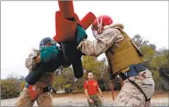  ??  ?? Two recruits are overseen by their drill instructor as they train to protect a bridge crossing during the pugil stick training on the bayonet course.