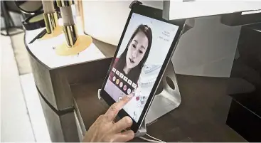  ??  ?? Mirror, mirror: A customer using a product tablet at a beauty shop in Shanghai. — Bloomberg