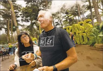  ?? Photograph­s by Carolyn Cole Los Angeles Times ?? MARK and Robin Ticknor of Oroville light up at Grass Lands, an area inside the Outside Lands festival in San Francisco where cannabis was legally sold and consumed. The permit was issued as part of a pilot project.