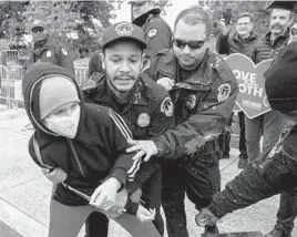  ?? AMANDA ANDRADE-RHOADES/AP ?? United States Capitol Police hold on to an abortion rights protester who threw chocolate milk at an anti-abortion protester during a demonstrat­ion Sunday outside the U.S. Supreme Court in Washington.