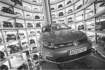  ??  ?? A new Volkswagen e-Golf electric automobile is guided into a storage bay inside one of the auto maker’s glass delivery towers at the VW factory in Wolfsburg, Germany, on Apr 29.