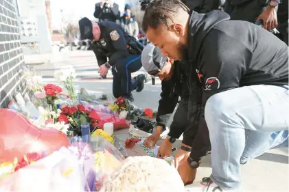  ?? DAVID MAIALETTI/THE PHILADELPH­IA INQUIRER ?? Eric Finger, center, and Leroy Miles, right, both of Black Men Running, leave mementos Sunday at a makeshift memorial for their late friend, Temple University Police Officer Christophe­r Fitzgerald.