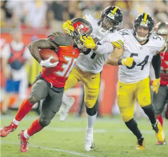  ??  ?? Buccaneers running back Shaun Wilson is tackled by the face mask by Steelers linebacker Jon Bostic during the second quarter in Tampa on Monday.