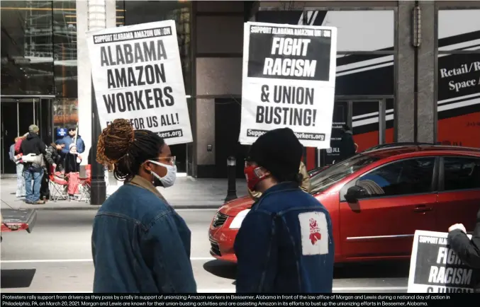  ??  ?? Protesters rally support from drivers as they pass by a rally in support of unionizing Amazon workers in Bessemer, Alabama in front of the law office of Morgan and Lewis during a national day of action in Philadelph­ia, PA, on March 20, 2021. Morgan and Lewis are known for their union-busting activities and are assisting Amazon in its efforts to bust up the unionizing efforts in Bessemer, Alabama.