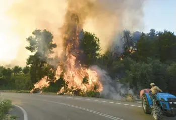  ?? GIANNIS SPYROUNIS/ILIALIVE.GR ?? A farmer drives near a wildfire Sunday in Krestena, Greece. Authoritie­s in the village and five others ordered people to flee. A Greek fire official said 141 fires had started in the country over the past three days. In California, a fire near Yosemite National Park continued to burn out of control and has grown into one of the state’s biggest blazes this year.