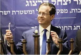  ?? OREN ZIV AP ?? Israeli President Isaac Herzog lights candles Sunday during the Jewish holiday of Hanukkah in the Israeli controlled part of the West Bank city of Hebron’s holiest site, known to Jews as the Tomb of the Patriarchs and to Muslims as the Ibrahimi Mosque.