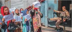  ?? AFP ?? A Taliban fighter watches as Afghan women hold placards during a demonstrat­ion in Kabul on Sunday.