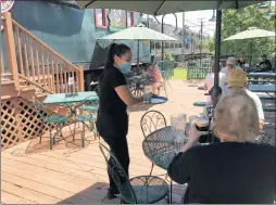  ?? TED SLOWIK/DAILY SOUTHTOWN PHOTOS ?? Pati Flores collects empty glasses from customers Friday after serving a fresh round of drinks at Flossmoor Station Restaurant & Brewery.