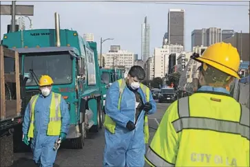  ?? Gabriella Angotti-Jones Los Angeles Times ?? MEMBERS OF the Cleaning and Rapid Engagement team worked around tents Tuesday on 7th Street. Mayor Eric Garcetti said he hopes to place homeless people in downtown hotel rooms during the pandemic.