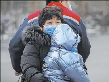  ?? Andy Wong The Associated Press ?? Family members wearing face masks ride on a tricycle Saturday in Beijing.
