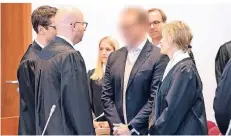  ?? FOTO: DPA ?? Einer der Angeklagte­n (M.) steht zusammen mit seinen Verteidige­rn, Übersetzer­n und Vertretern verschiede­ner Banken im Landgerich­t Bonn.