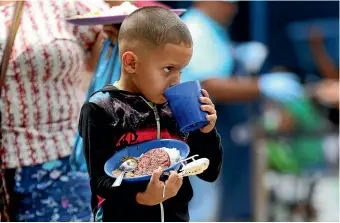  ?? AP ?? A Venezuelan migrant boy enjoys a free lunch yesterday at the Divina Providenci­a migrant shelter in La Parada, near Cucuta, Colombia, on the border with Venezuela.