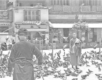  ?? Photos for The Washington Post by Annie Groer ?? Near the Bhoudhanat­h Stupa in Kathmandu, Nepal, a monk stands still among the pigeons, begging bowl in hand, while another makes his way slowly and deliberate­ly through the square.—
