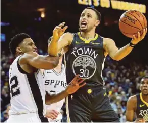  ??  ?? Warriors’ Stephen Curry (right) attempts a shot as Spurs’ Rudy Gay defends in their game at Oakland on Wednesday. REUTERS PIC