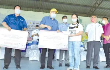  ??  ?? Hajiji handing over the one-off cash aid to one of the livestock operators in Kota Marudu held at the Pentas Utama, Dataran Kota Marudu.