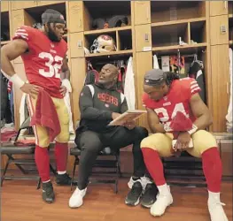  ?? Michael Zagaris Getty Images ?? SAN FRANCISCO 49ERS assistant Anthony Lynn chats with running backs Tyrion Davis-Price (32) and Jordan Mason (24) in the locker room before a game.