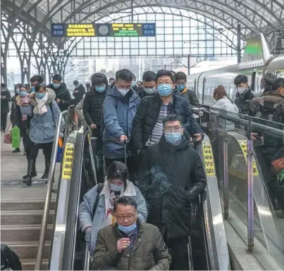  ?? / EFE ?? Pasajeros con mascarilla­s protectora­s y su equipaje en la estación de tren de Hankou, en Wuhan (China).