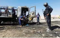  ?? - Reuters ?? WRECKAGE: Rescue workers inspect as a policeman stands near a truck after a blast in Quetta, Pakistan on October 18, 2017.