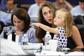  ?? MANUEL BALCE CENETA / ASSOCIATED PRESS ?? U.S. Rep. Jaime Herrera Beutler (center), R-Wash., holds her daughter, Abigail, as she sits next to U.S. Rep. Martha Roby, R-Ala., during a hearing Wednesday on congressio­nal spending bills. A Republican fiscal plan proposes deep cuts to safety net...