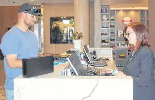  ?? JIM DAY/THE GUARDIAN ?? Front desk agent Amber Murphy checks Chris Curwin of Port Hope, Ont., into the Hampton Inn and Suites hotel in Charlottet­own, which opened on June 27. Constructi­on on the $15-million, six-storey hotel with 124 rooms began in the fall of 2017.