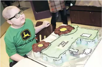  ??  ?? Above: Huntre Allard poses next to his custom-made tractor cake at Our Lady of Perpetual Help Catholic Elementary School during his first day back in class on Monday.