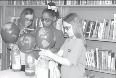  ?? Brittany Williams/News-Times ?? Experiment: Hugh Goodwin students Alysa Wilson, Jordynn Clark and Leeann Ramey experiment with CO2 during a Great Lakes sponsored Earth Day event.