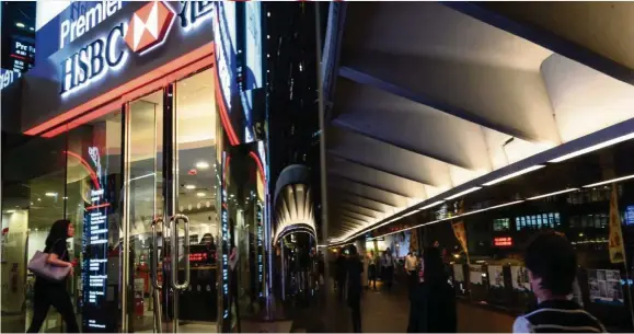  ?? — AFP ?? Profit down: A woman is seen walking towards a HSBC branch in Hong Kong’s Central District recently. HSBC’S pre-tax profit slips 18% to Us$4.8bil in the third quarter.