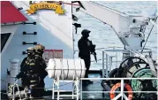  ??  ?? Police officers help migrants to disembark from the merchant ship El Hiblu 1 in Valletta’s Grand Harbour, right; Maltese army forces stand on board the tanker, above