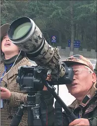  ?? ZHANG XIAOMIN / CHINA DAILY ?? Gu Guoqiang takes pictures of birds during the race held in Lyushun in Dalian, Liaoning province.