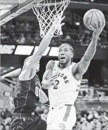  ?? JOHN RAOUX THE ASSOCIATED PRESS ?? Raptors' Kawhi Leonard makes a shot against Magic's Aaron Gordon, left, during the first half in Orlando, Fla., on Tuesday. Raptors won, 93-91.